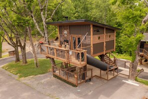 A multi-level wooden cabin with a fireplace, outdoor seating, and a slide.