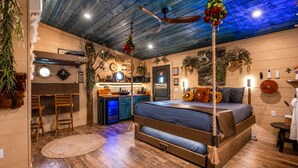 Ein rustikales Schlafzimmer mit Bett, Holzbalkendecke und Deckenventilator.