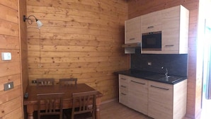 Una cocina compacta con muebles de madera, una encimera negra y una mesa de comedor con sillas.