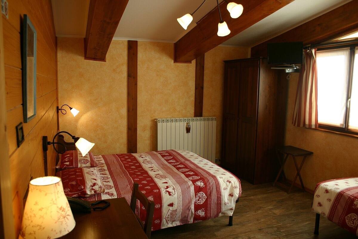 A bedroom with a bed, bedside tables, a lamp, a radiator, and a window with curtains.