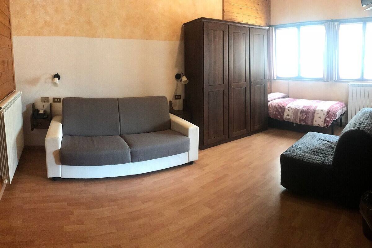 A small room with a sofa, a bed, a cabinet, and a radiator.