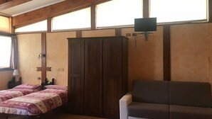 Una habitación con techo de madera, un armario grande, un sofá y una cama con ropa de cama estampada.