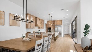 A modern kitchen with wooden cabinets, a central island, and pendant lighting. - Desert Gem 7 Bedroom Home (St. George)