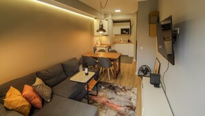 Ett modernt vardagsrum med soffa, matbord och köksdel.