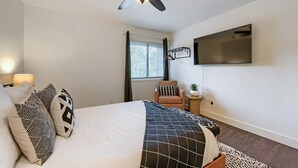 A bedroom with a bed, pillows, a ceiling fan, a mounted TV, a window with blinds, and a small side table with a plant. - 37c Hidden Creek Mountain Getaway! 3 Bedroom Condo by RedAwning (Park City)