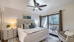 A bedroom with a bed, bedside tables, a nightstand, a ceiling fan, a window with curtains, and a view of trees outside. - 37c Hidden Creek Mountain Getaway! 3 Bedroom Condo by RedAwning (Park City)