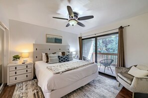 A bedroom with a bed, bedside tables, a nightstand, a ceiling fan, a window with curtains, and a view of trees outside. - 37c Hidden Creek Mountain Getaway! 3 Bedroom Condo by RedAwning (Park City)