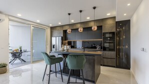 A modern kitchen with a central island, two bar stools, and pendant lighting. - Carmen - 2 Bedroom Apartment - Downtown (Split)