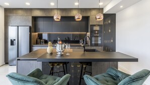 A modern kitchen with a central island, stainless steel appliances, and pendant lighting. - Carmen - 2 Bedroom Apartment - Downtown (Split)