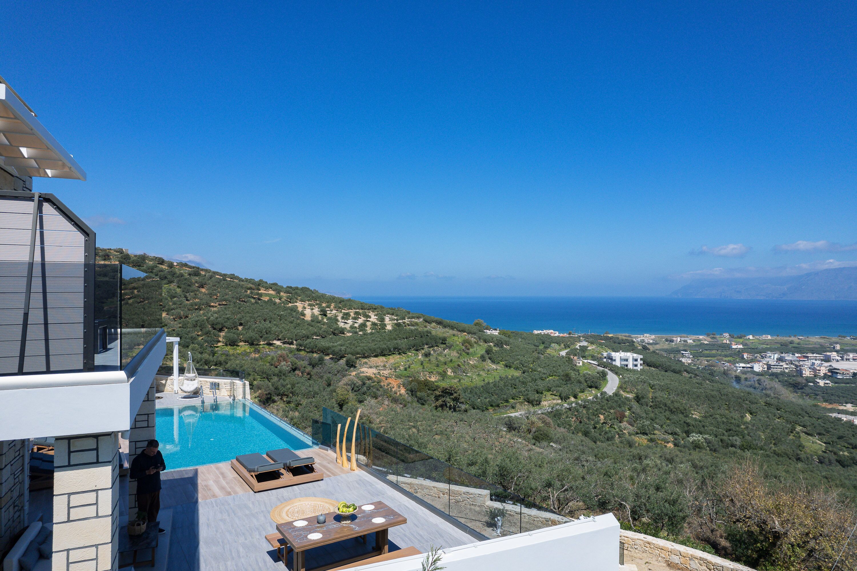A rooftop pool with a view of the sea and hills.
