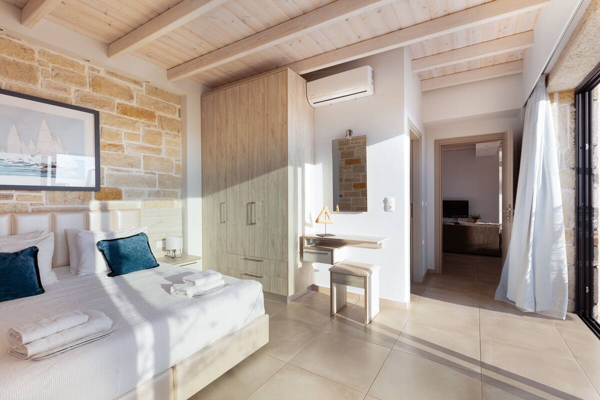 Quarto moderno com cama, escrivaninha e banheiro.