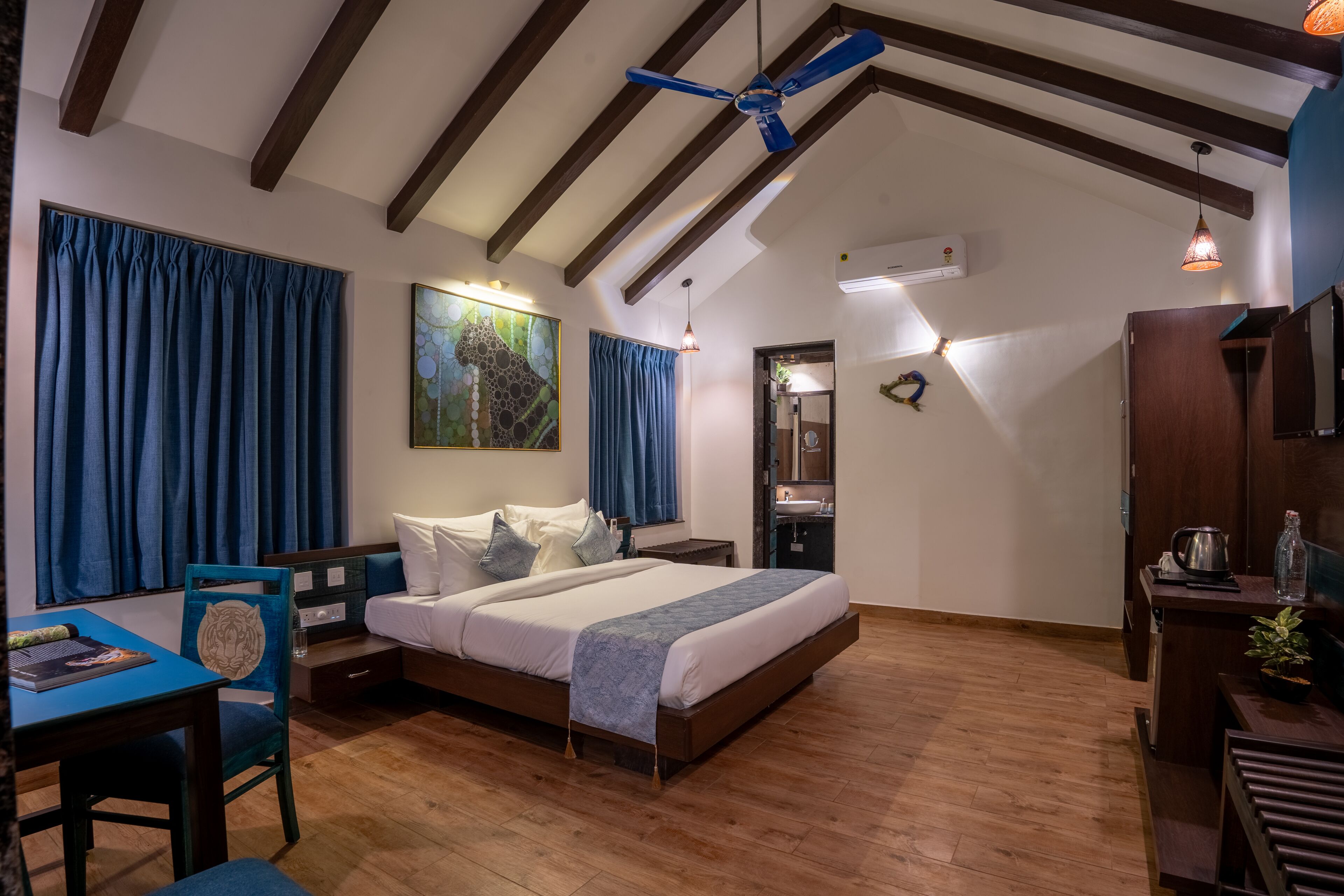 Een slaapkamer met een bed, een bureau, een stoel, een plafondventilator en een schilderij aan de muur.