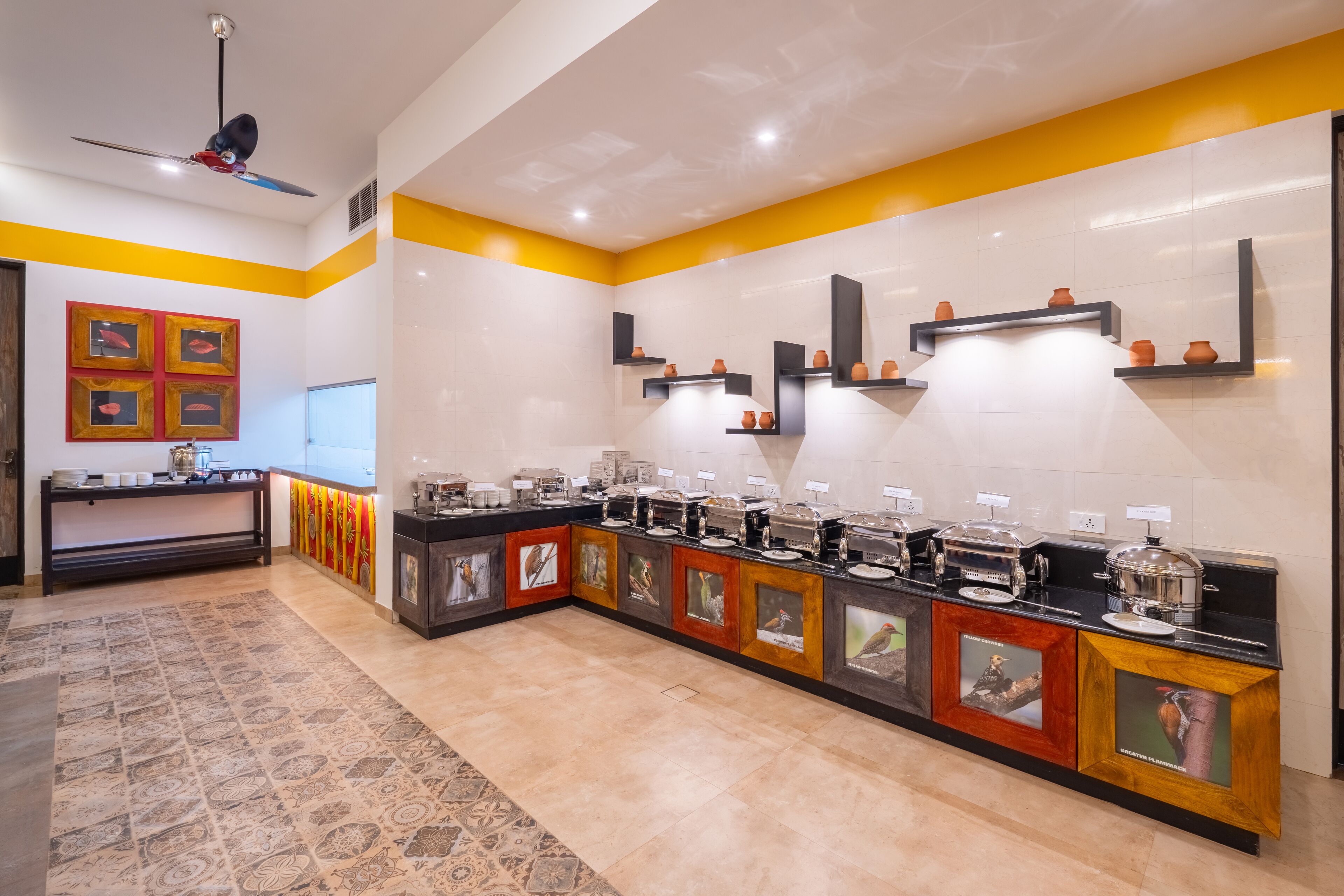A modern kitchen with a long counter, multiple coffee stations, and decorative wall art.