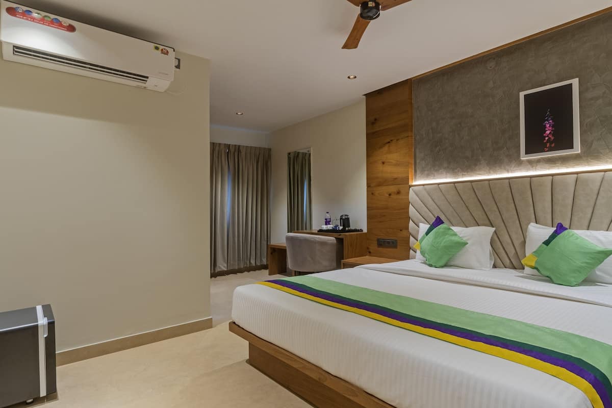 Une chambre d’hôtel équipée d’un lit, d’un bureau, d’un climatiseur et d’un ventilateur de plafond.