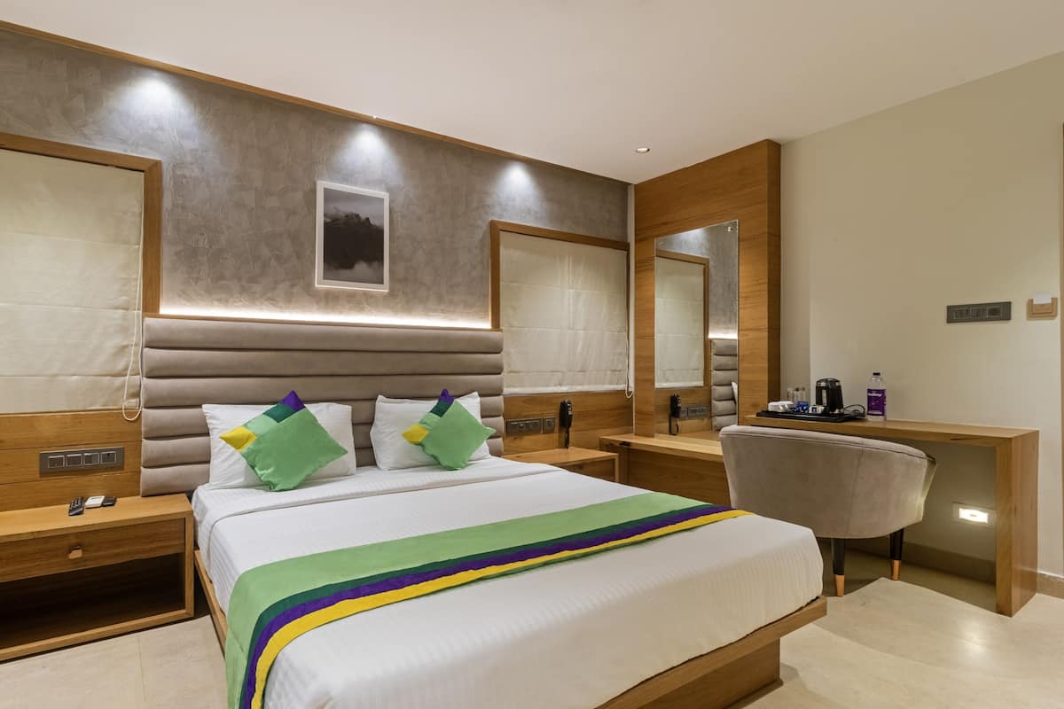 Une chambre d’hôtel moderne avec un grand lit, des tables de chevet, un bureau et un miroir.