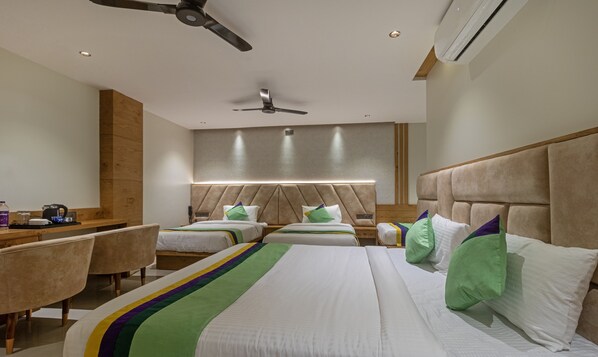 A hotel room with two beds, a desk, chairs, a ceiling fan, and an air conditioning unit.