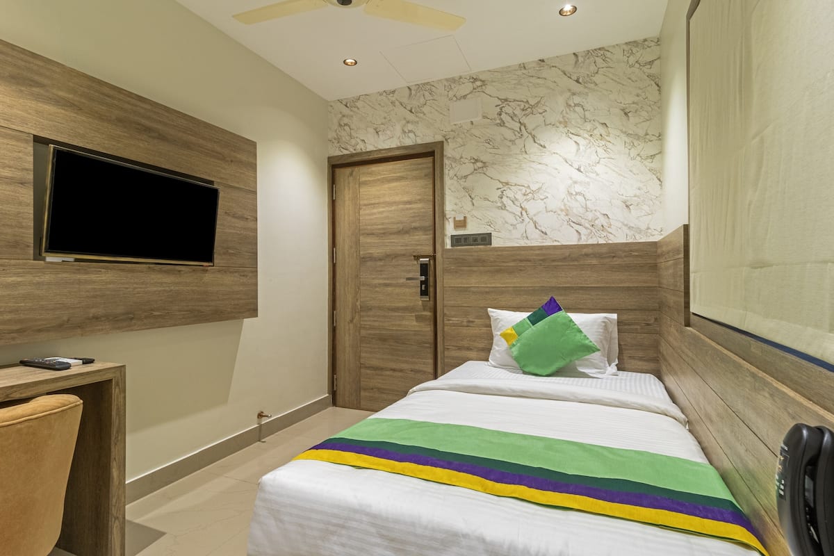 Une chambre d’hôtel avec un lit, un bureau, une télévision et une porte.
