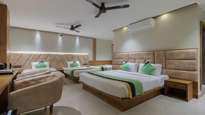 Een hotelkamer met twee bedden, een bureau, een stoel, een plafondventilator en een airconditioner.