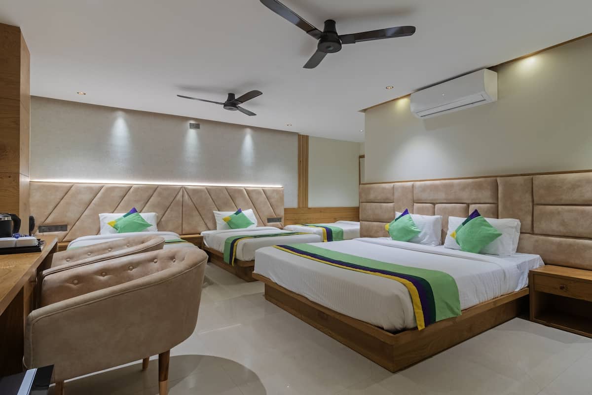 Une chambre d’hôtel avec deux lits, un bureau, une chaise, un ventilateur de plafond et un appareil de climatisation.
