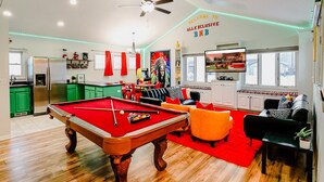 A spacious living room with a pool table, a television, and a red carpet.