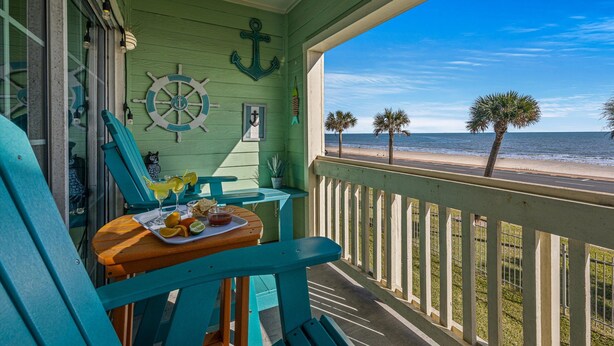 A balcony with a view of the beach, a table with drinks, and a chair. - Beautiful Ocean & Beach Front Condo~Sleeps 5 - Amazing Views! (Galveston)