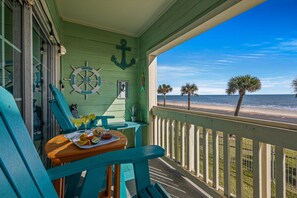 A balcony with a view of the beach, a table with drinks, and a chair. - Beautiful Ocean & Beach Front Condo~Sleeps 5 - Amazing Views! (Galveston)