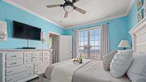 A bedroom with a bed, a dresser, a television, and a window with curtains. - Beautiful Ocean & Beach Front Condo~Sleeps 5 - Amazing Views! (Galveston)