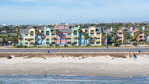 A beachfront hotel with colorful buildings, a sandy beach, and the ocean. - Beautiful Ocean & Beach Front Condo~Sleeps 5 - Amazing Views! (Galveston)