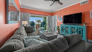 A living room with a sofa, a coffee table, a TV, and a ceiling fan. - Beautiful Ocean & Beach Front Condo~Sleeps 5 - Amazing Views! (Galveston)