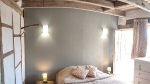 Een slaapkamer met een bed, bedlampen, een nachtkastje en een dressoir.