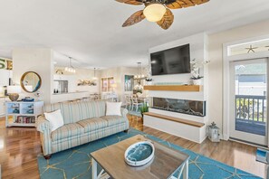 A living room with a sofa, coffee table, TV, fireplace, and a ceiling fan.