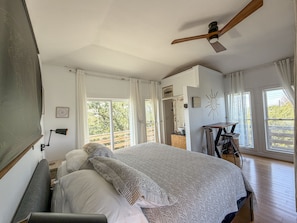 Une chambre à coucher avec un lit, un bureau et un ventilateur de plafond.