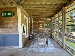 Une cabane en bois avec une enseigne indiquant « FRUITS DE MER », et un intérieur rustique comprenant une table et des chaises en bois.