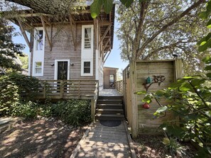 Une maison en bois avec un porche, un escalier et un petit jardin.