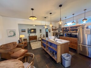 Een moderne keuken met een centraal eiland, roestvrijstalen apparatuur en hanglampen.