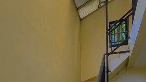 A staircase with yellow steps and a black railing, leading to a landing with a red floor. - AJ Bike Guesthouse Syariah (Yogyakarta)