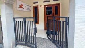 A gated entrance to a building with a sign for 'AJ Bike Guest House' and the number '83' above the door. - AJ Bike Guesthouse Syariah (Yogyakarta)