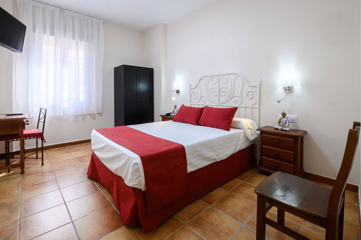 A bedroom with a bed, a wardrobe, a desk, and a chair.