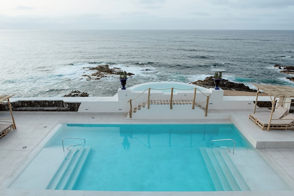 Una piscina al aire libre, camas de piscina con cargo, sombrillas
