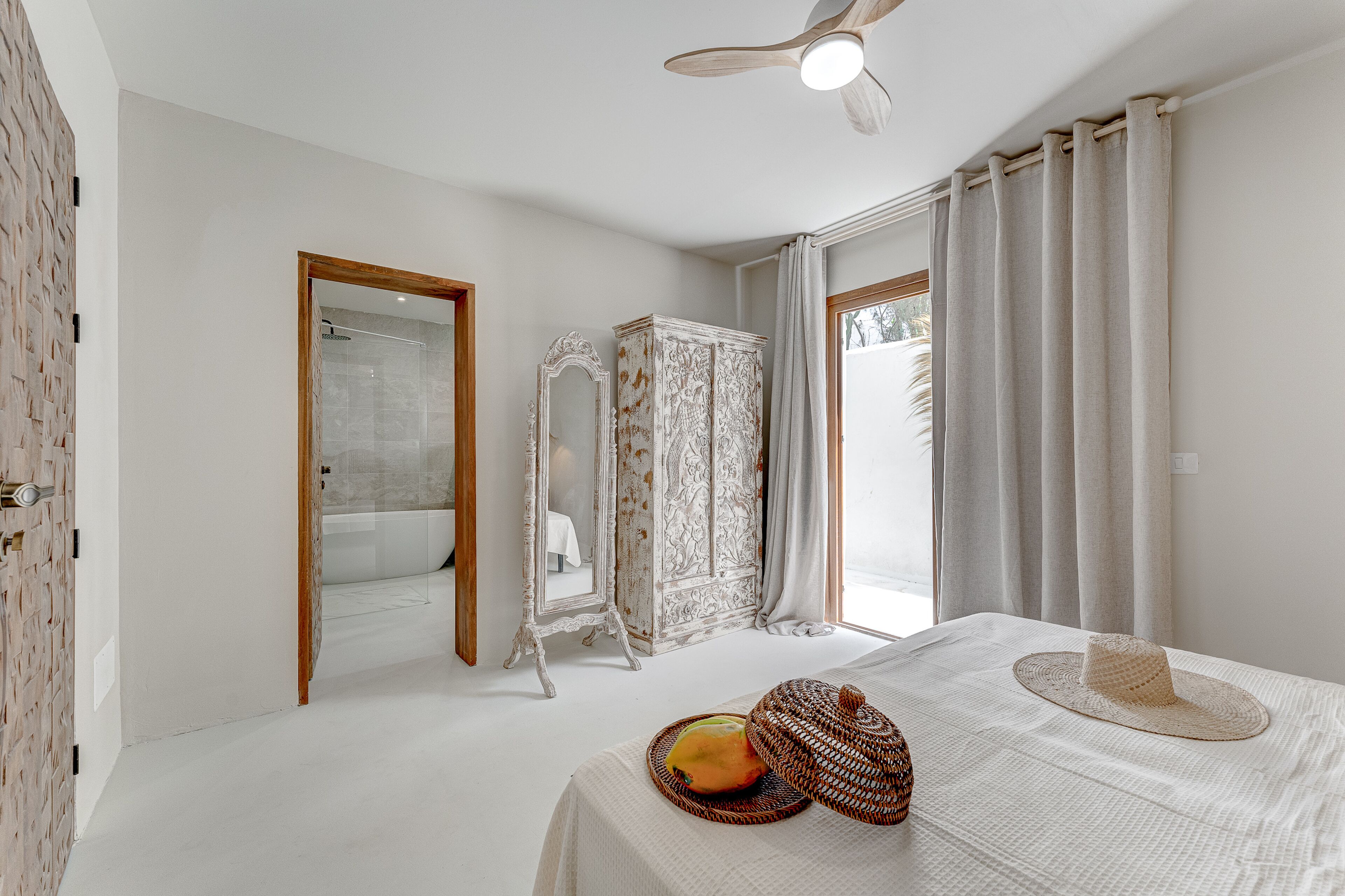 Quarto com cama, ventoinha no teto, guarda-roupa e espelho.