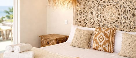 Un dormitorio con una cama grande, un cabecero decorativo, una lámpara colgante y vistas al exterior.