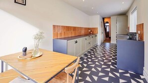 Eine moderne Küche mit einem Holzespeisetisch, einem Boden mit geometrischem Muster und Blick in den Wohnbereich.