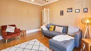 Ein Wohnzimmer mit einer Couch, einem Sessel und einer Lampe.