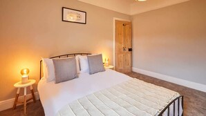 Ein Schlafzimmer mit einem Bett, Nachttischlampen, einer Holztür und einem gerahmten Bild an der Wand.