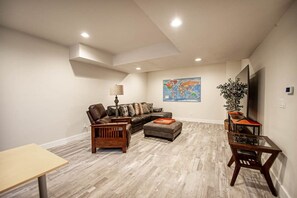 Una sala de estar amplia con un sofá modular, una mesa de centro, una mesita de noche de madera y una mesa con cubierta de vidrio.