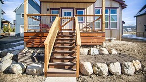 A wooden staircase leading to a covered porch with a view of a house.
