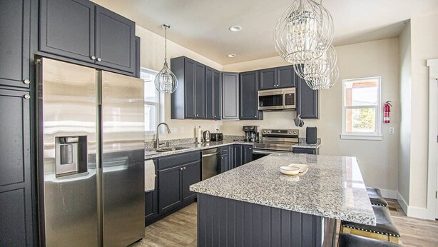 A modern kitchen with dark cabinetry, stainless steel appliances, and a central island.