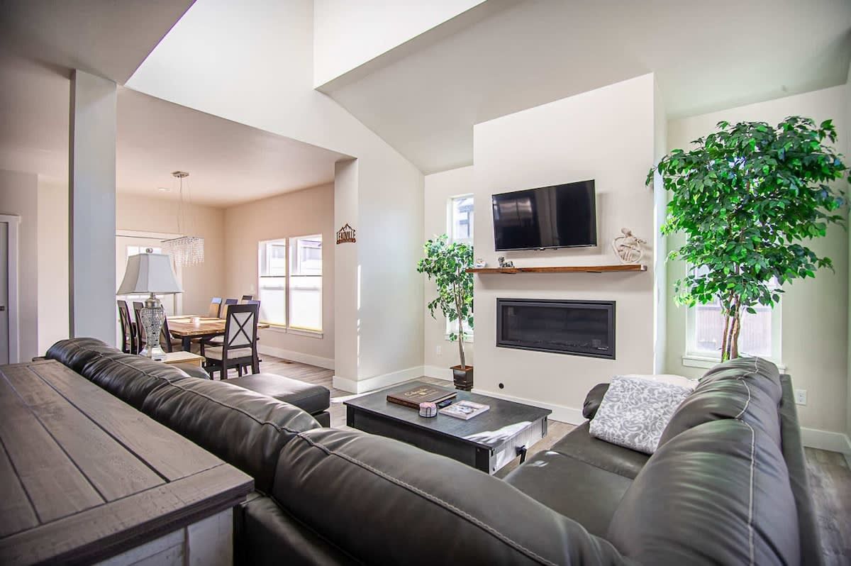 A modern living room with a sofa set, a coffee table, a fireplace, and a television.