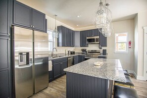 Una cocina moderna con muebles oscuros, electrodomésticos de acero inoxidable y una isla central.