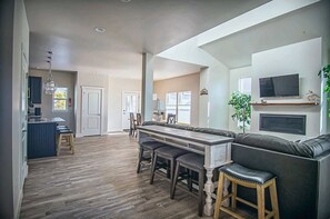 A modern kitchen with a dining area, wooden flooring, and a built-in TV.